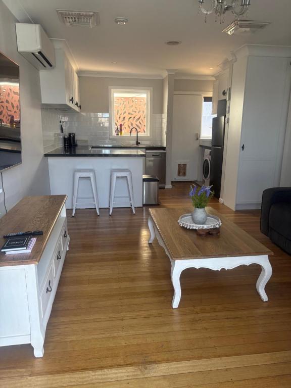 a living room with a table and a kitchen at Willow Place in Mornington