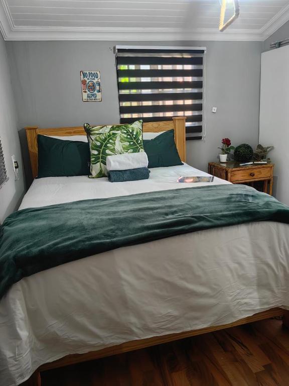 a bedroom with a large bed with green and white sheets at The Hideaway Cabin in Pretoria