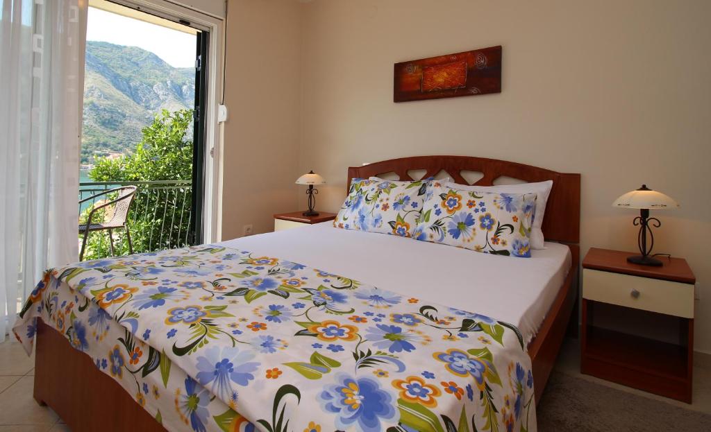 um quarto com uma cama com uma colcha floral e uma janela em Apartments Kordić em Kotor