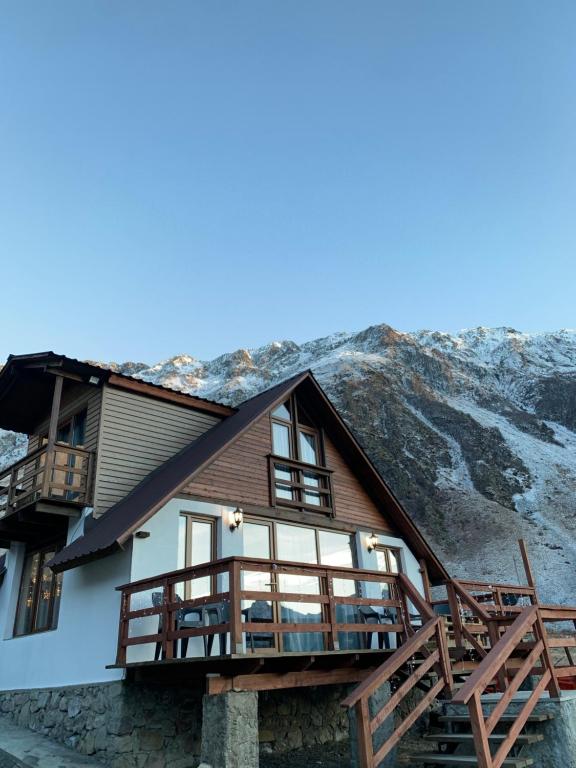 a house with a balcony and mountains in the background at old white house in Kazbegi