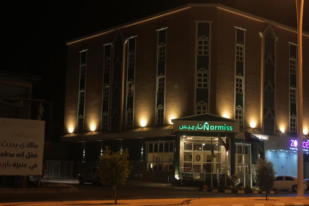 a large building with a sign that reads luxury apartments at night at Narmiss Aparthotel in Unayzah