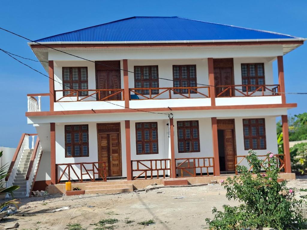 a white house with a blue roof at Karibu House Bwejuu in Bwejuu