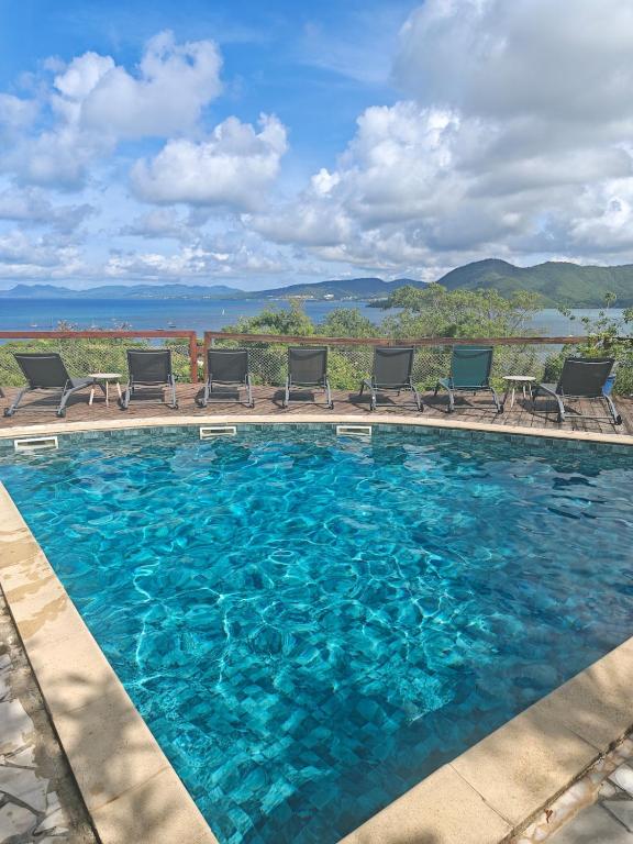 a swimming pool with chairs and blue water at Lodge Ti Bonheur in Sainte-Anne