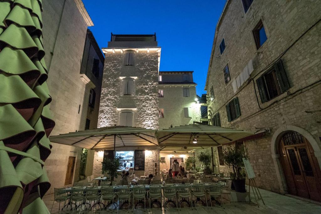 eine Terrasse mit Tischen und Sonnenschirmen vor einem Gebäude in der Unterkunft Murum Heritage Hotel in Split