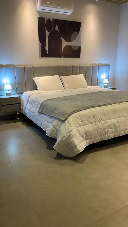 a bedroom with a large bed with two lights on it at Condômino Max life in Pipa