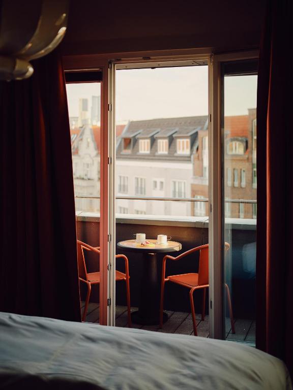 a room with a bed and a window with a table and chairs at The Dean Berlin in Berlin