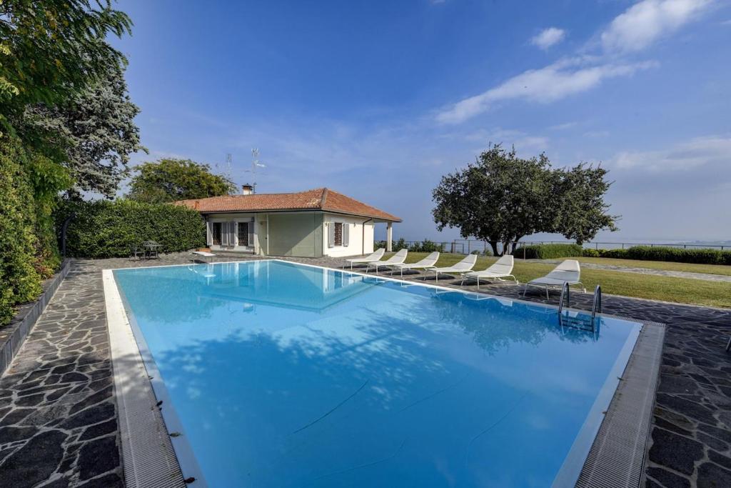 a swimming pool with chairs and a house at Villa Mirador in Padenghe sul Garda