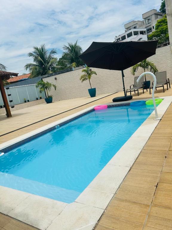 a swimming pool with an umbrella next to a building at House in Iriri in Anchieta