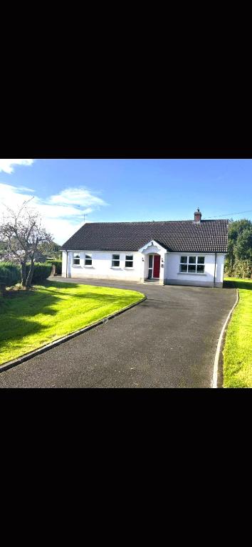 a white building with a driveway in front of it at Orchard Cottage in Loughgall
