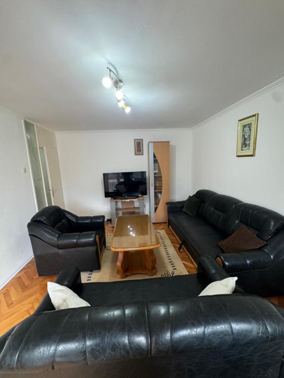 a living room with black leather couches and a coffee table at Apartman Jojo in Čapljina