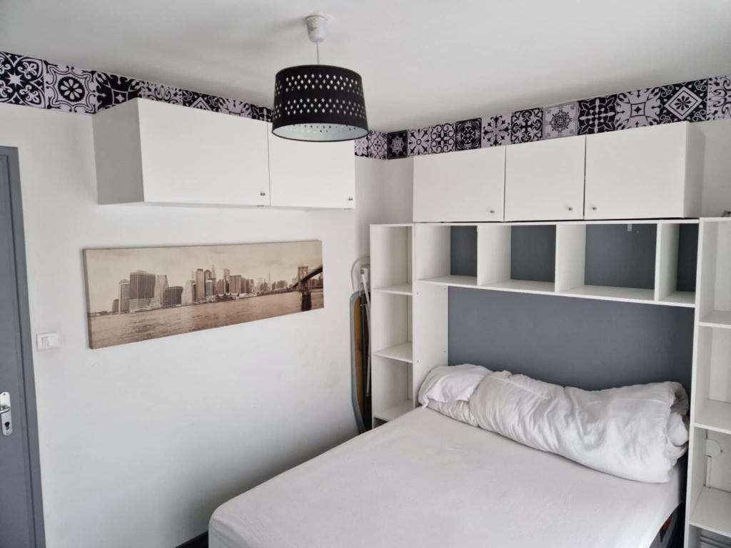 una camera da letto con un letto bianco e armadi bianchi di PapayaCalais a Calais