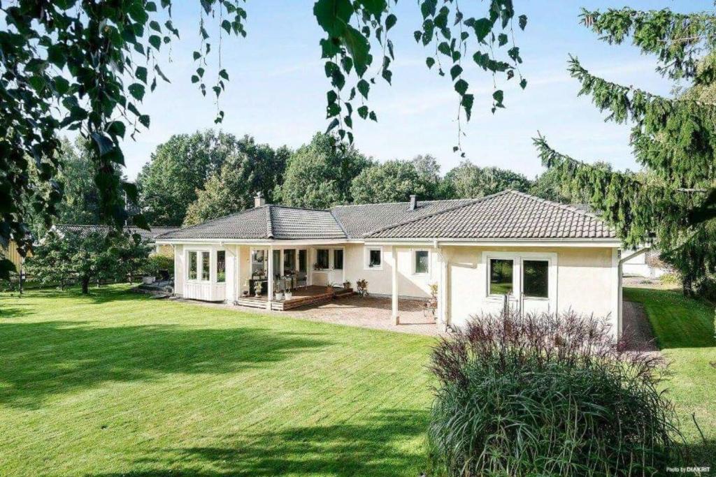 a white house with a large yard at Charming villa near the beach in Vejbystrand SE01066 in Vejbystrand