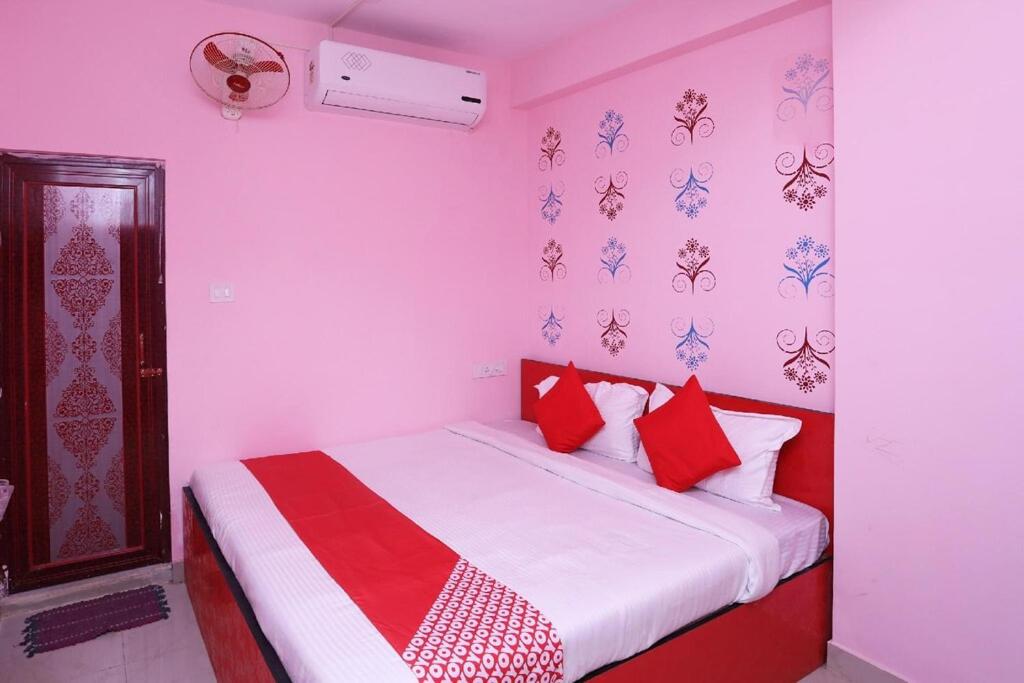 a bedroom with a bed with red and white pillows at Star Hospitality in kolkata