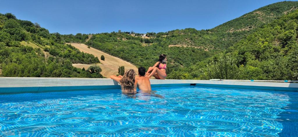 two women sitting on the edge of a swimming pool at Borgo Canapegna - Boschetto - private pool exclusive use in Fabriano