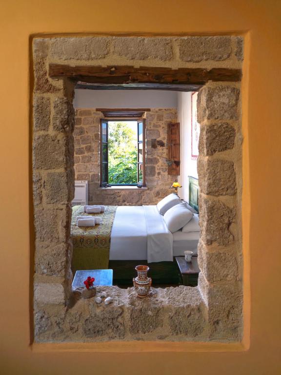 a bedroom with a bed in a stone wall at Colours - Old Town - Studios in Rhodes Town