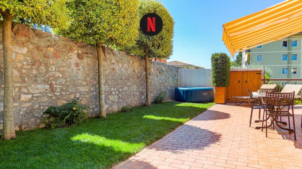 een patio met een tafel en stoelen naast een stenen muur bij MillyHolidays - Apartment Sunflower - Center - Nearby Beach - Private Garden - Spa Pool in Bardolino