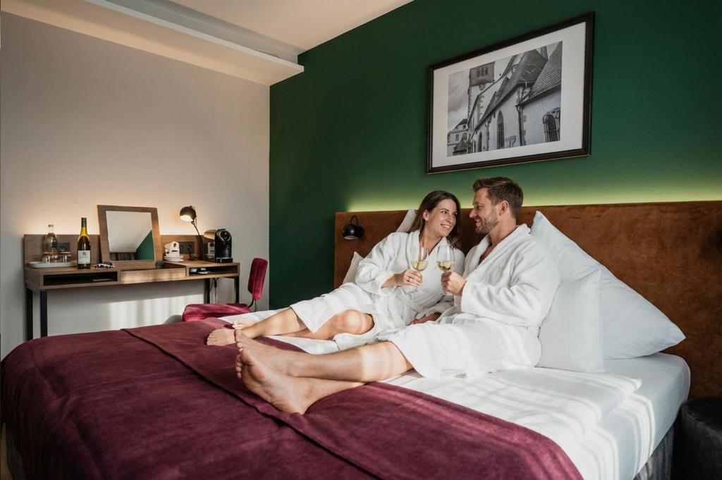 een man en een vrouw zitten op een bed bij Das Mühlentor Hotel in Bad Kreuznach
