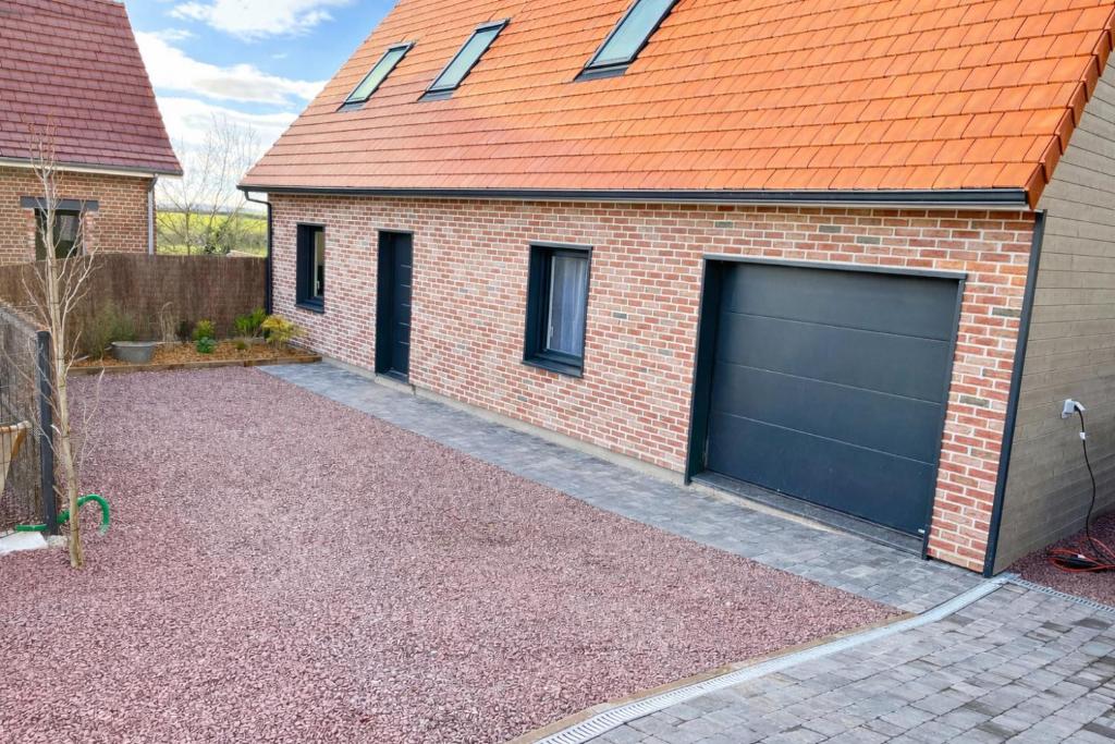 a garage with an orange roof and a garage door at Gîte Familial in Nabringhen