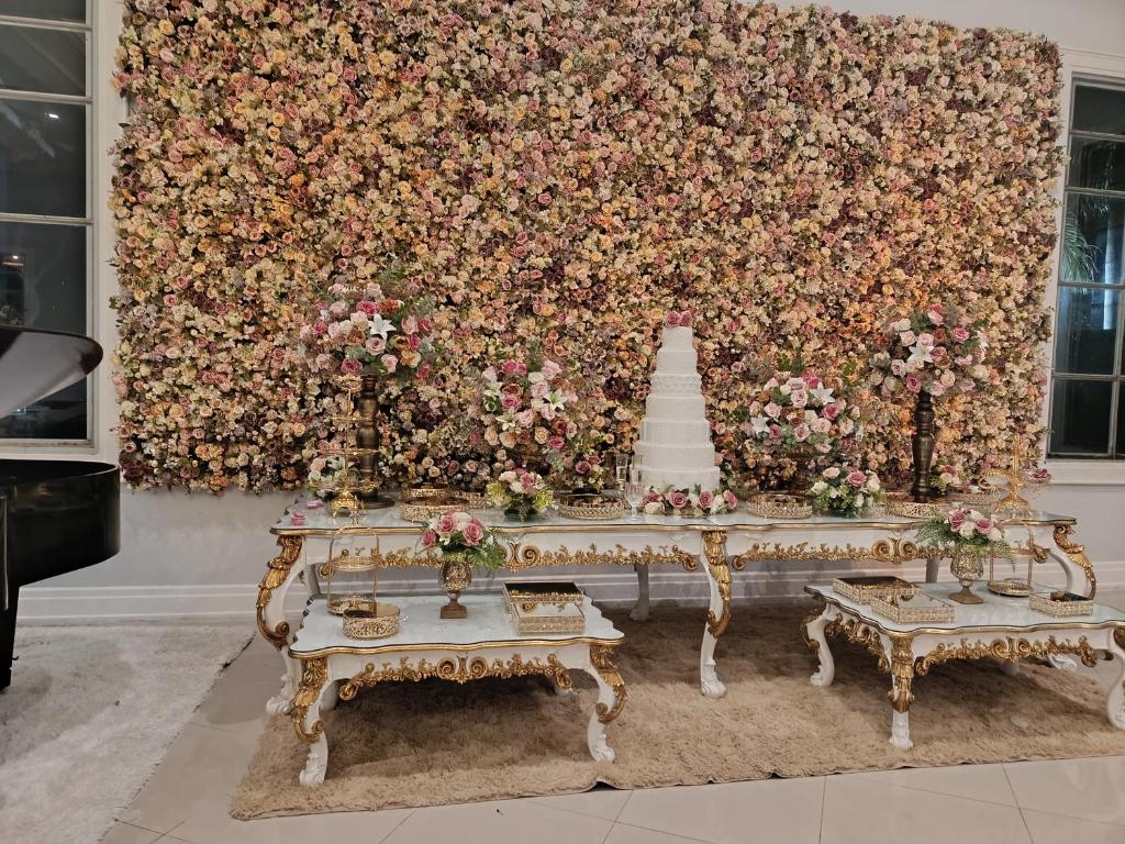 Eine Blumenwand mit einer Hochzeitstorte auf einem Tisch in der Unterkunft Dan in Cotia