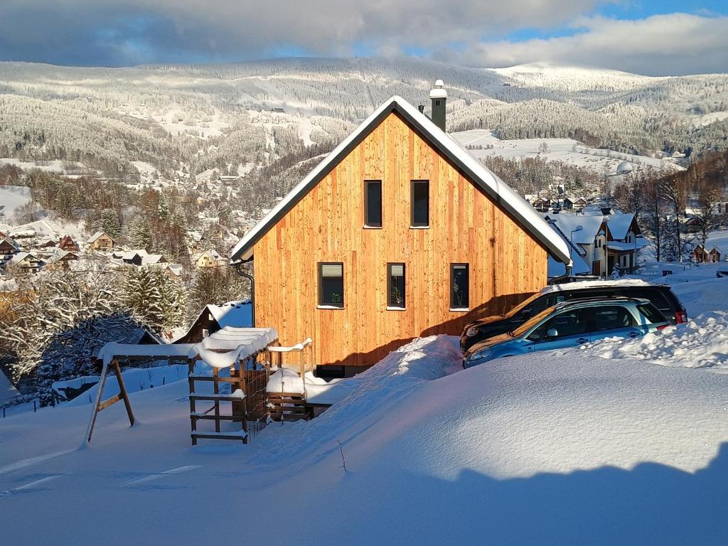 a wooden house with a car in the snow at Výhledovka chalet in Rokytnice nad Jizerou