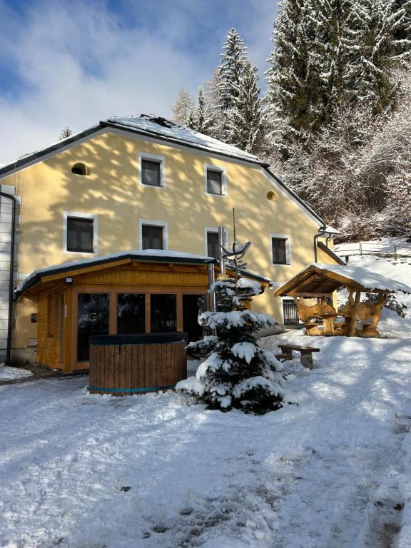 a large building in the snow with a tree at Groppenstein Apartmanház in Obervellach