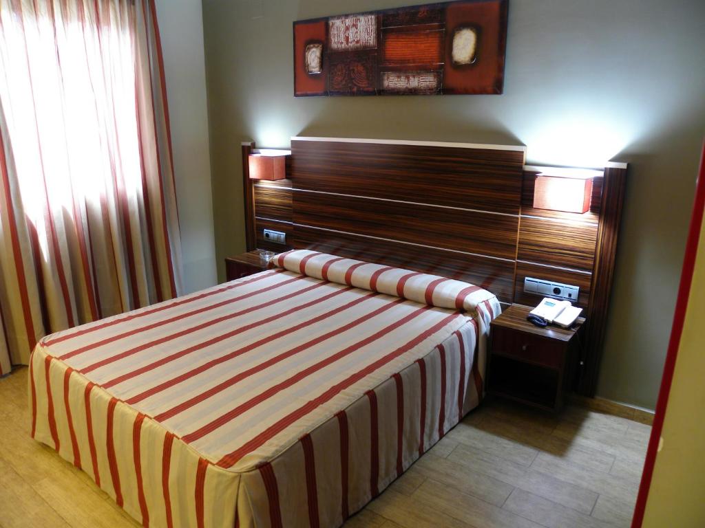 a bedroom with a bed with a wooden headboard at Hotel Noguera El Albir in Albir