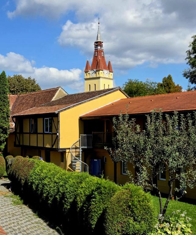 a yellow building with a clock tower on top at Transylvanian Nest in Cristian