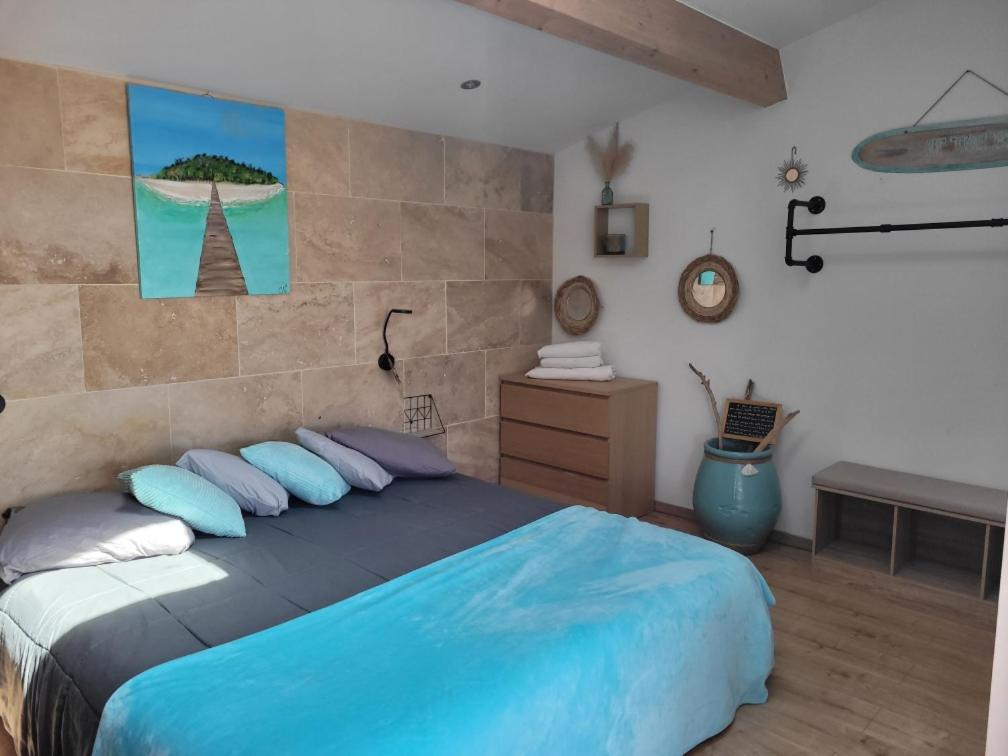 a bedroom with a large bed with blue pillows at O'sun avec jacuzzi privatif in Frontignan