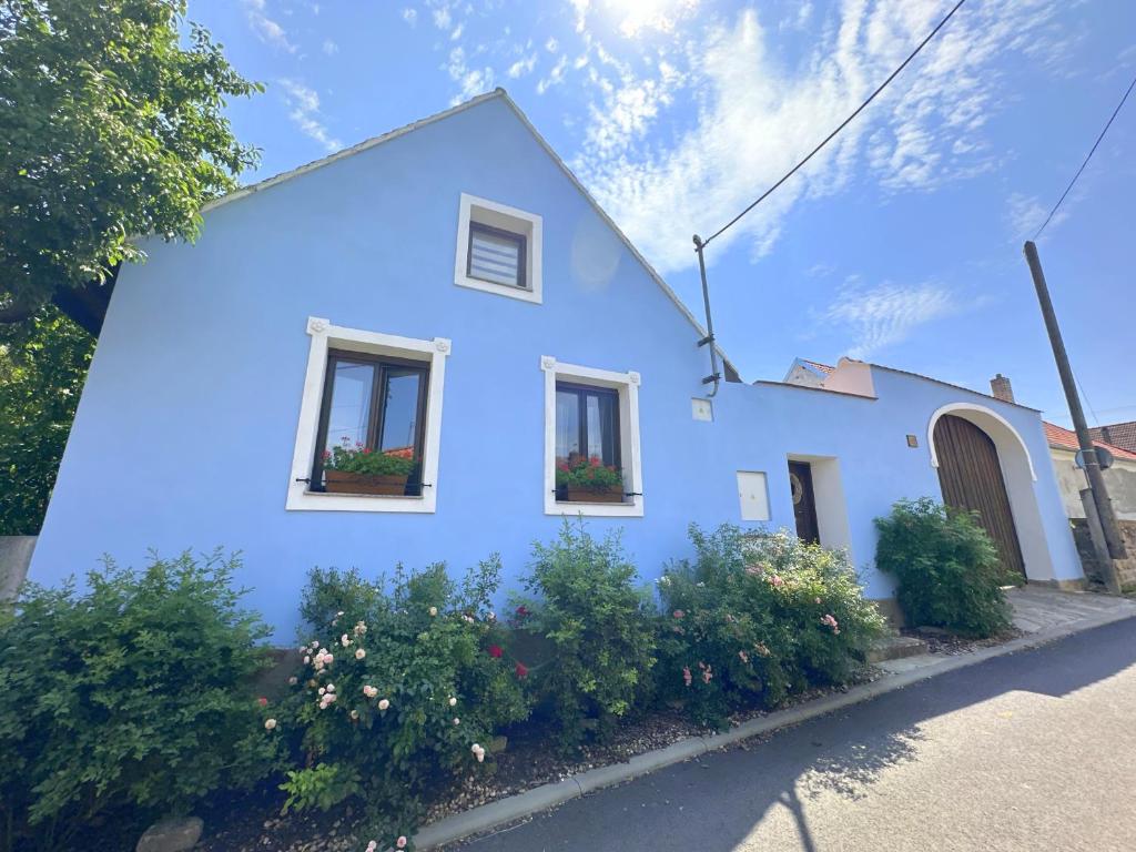 a blue house with flowers in the windows at Chalupa Za Vraty Jevišovice in Jevišovice