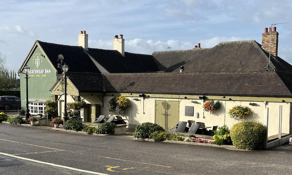 a white building with couches in front of a street at Wheatsheaf Inn, Bar Hill in Onneley