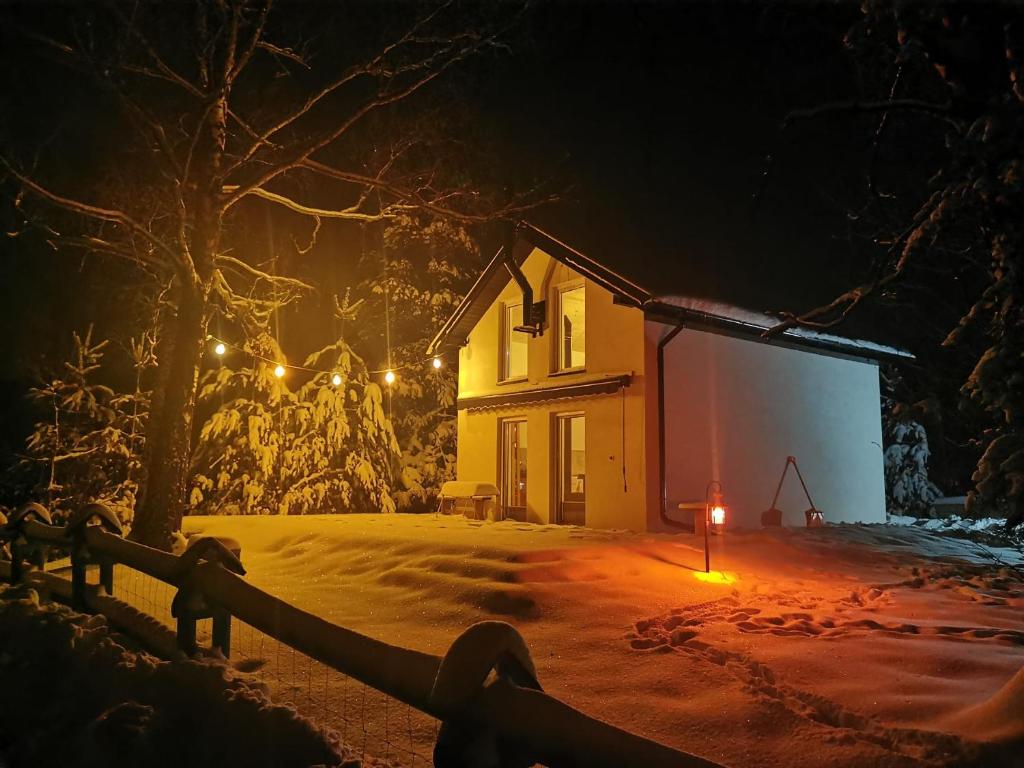 a house with a light in the snow at night at Chata z Kraja in Józefów
