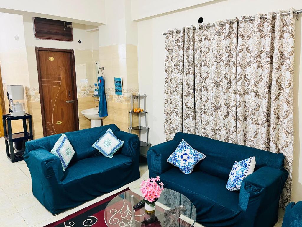 un soggiorno con un divano blu e un tavolo di vetro di Paradise Suite's a Dhaka