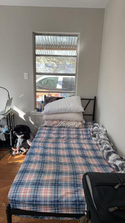 a bedroom with a bed with a plaid blanket and a window at Only 25 dollars-Man's bed in a room in Texas City