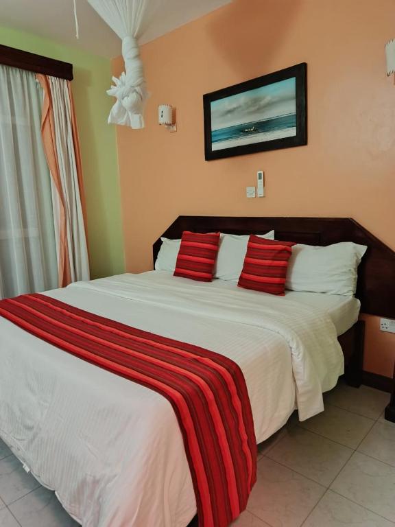 a bedroom with a large white bed with red pillows at Raya hotel Nyali Mombasa in Mombasa