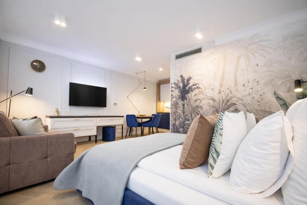 a bedroom with a bed and a couch and a tv at InPoint Smart Apartments in Krakow