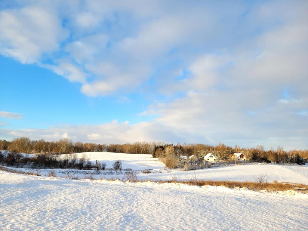 een met sneeuw bedekt veld met een huis op de achtergrond bij Wyskok 1 - dom z widokiem in Srokowo
