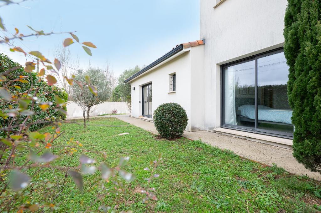 a house with a large window in a yard at Maison Épure - maison mitoyenne avec jardin in Colomiers