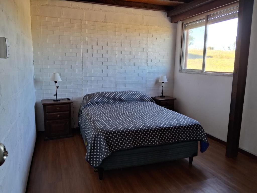 una camera con un letto e due comodini con finestra di La Buonaterra -Cabañas con playa privada sobre el Rio Uruguay a Fray Bentos