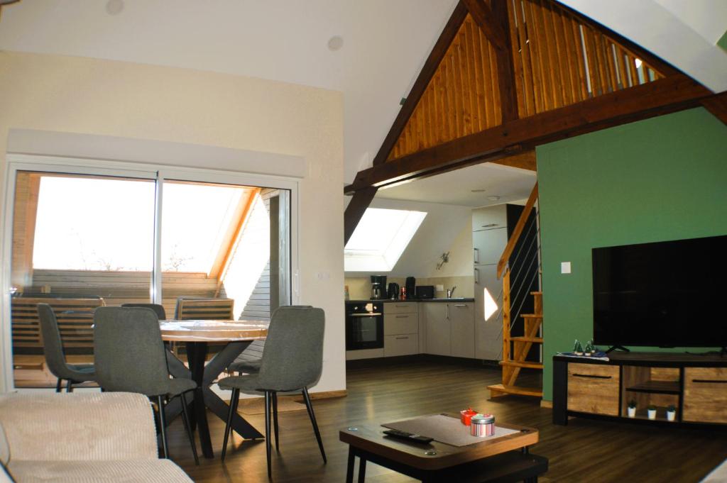 a living room with a table and a living room with a television at La Grange de Pépé in Biltzheim