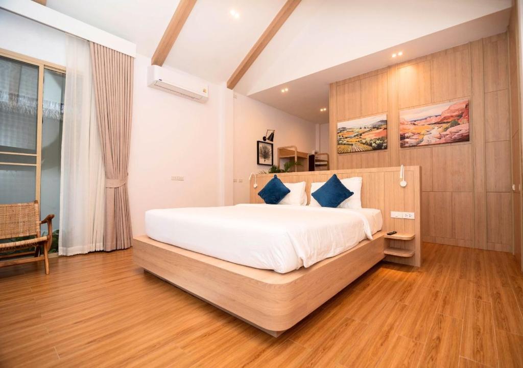 a bedroom with a large white bed with blue pillows at The Poom Cafe & Resort Khao Yai in Ban Khanong Phra Klang (1)