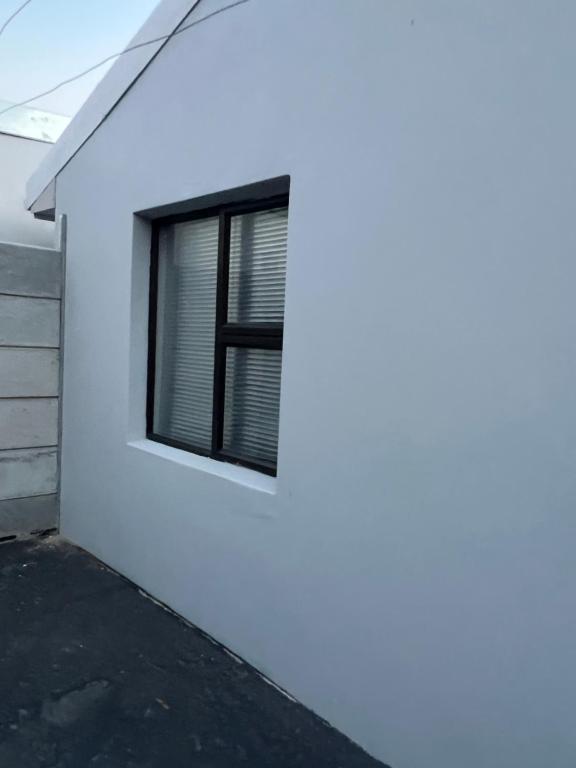 a white house with a window on the side of it at Oryx guest house in Oakdale