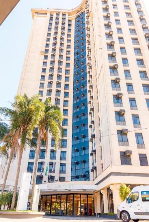 een groot gebouw met palmbomen ervoor bij Espaço Flat Aeroporto de Congonhas in Sao Paulo