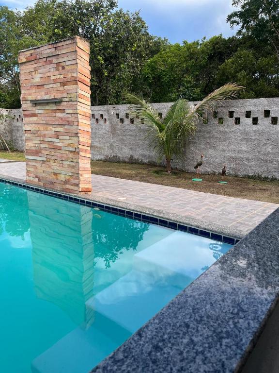 a swimming pool with blue water and a brick wall at Chácara Fim de Tarde in Barra do Garças