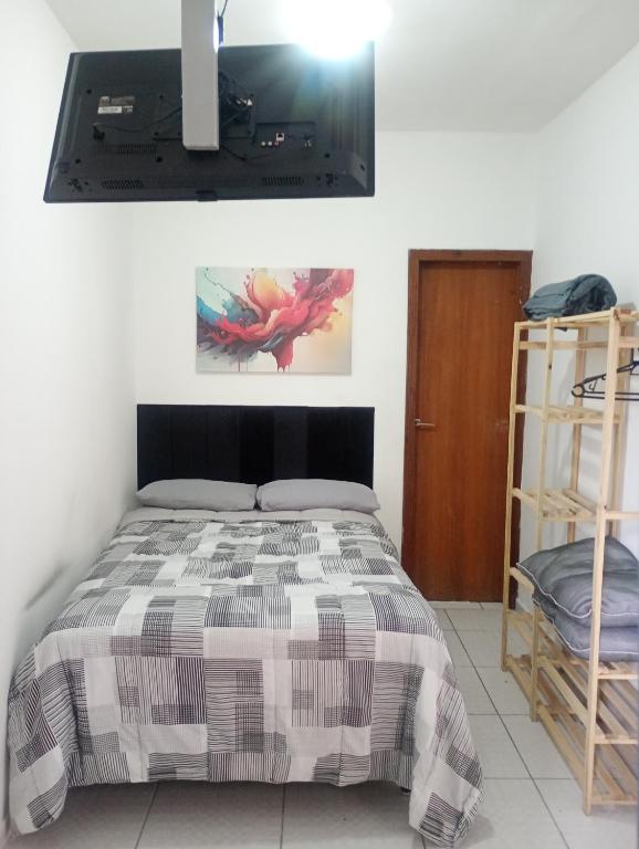 a bedroom with a bed and a tv on the wall at Suíte casal Bela Vista 207 in São Paulo