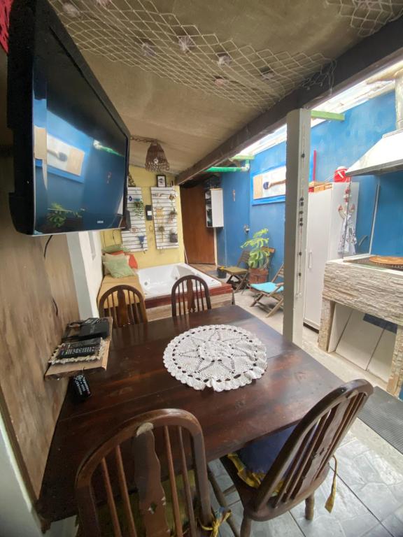 a dining room with a table and a tv on a wall at Hospedagem Mandala in Ubatuba