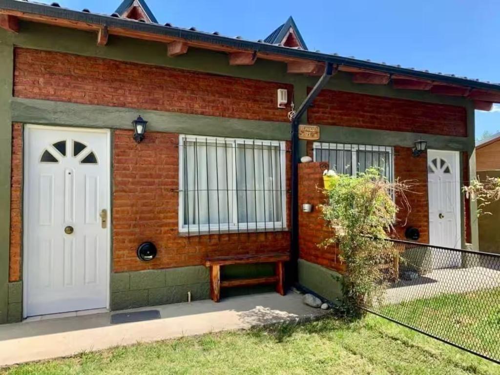 a brick house with white doors and a bench at Duplex lo de Aaron in El Bolsón