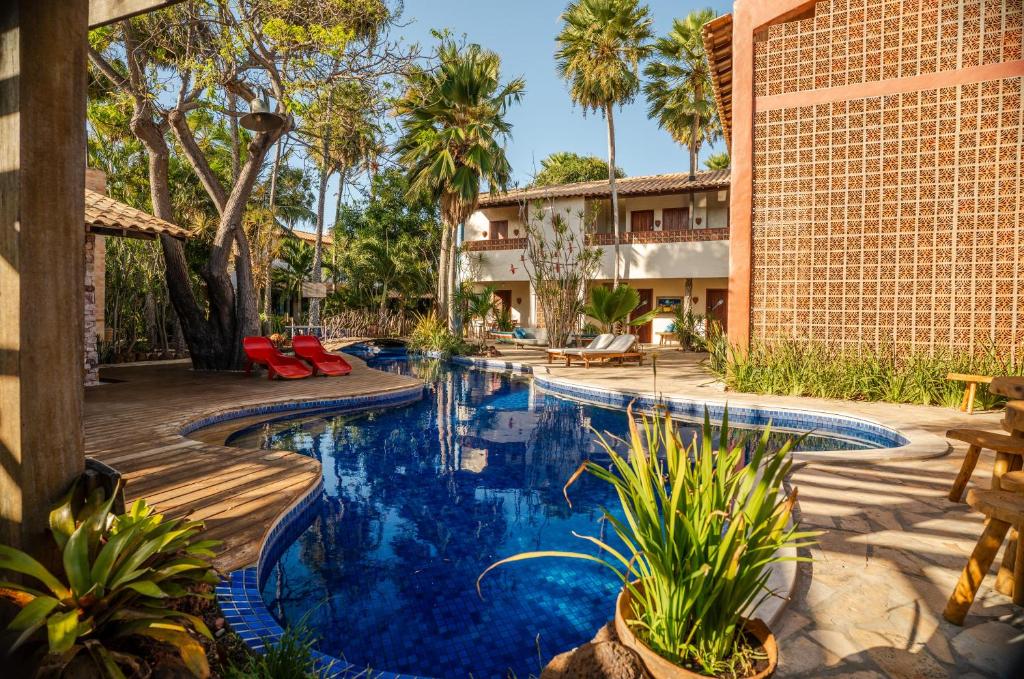 an outdoor pool with palm trees and a building at Pousada Vila Parnaíba in Parnaíba