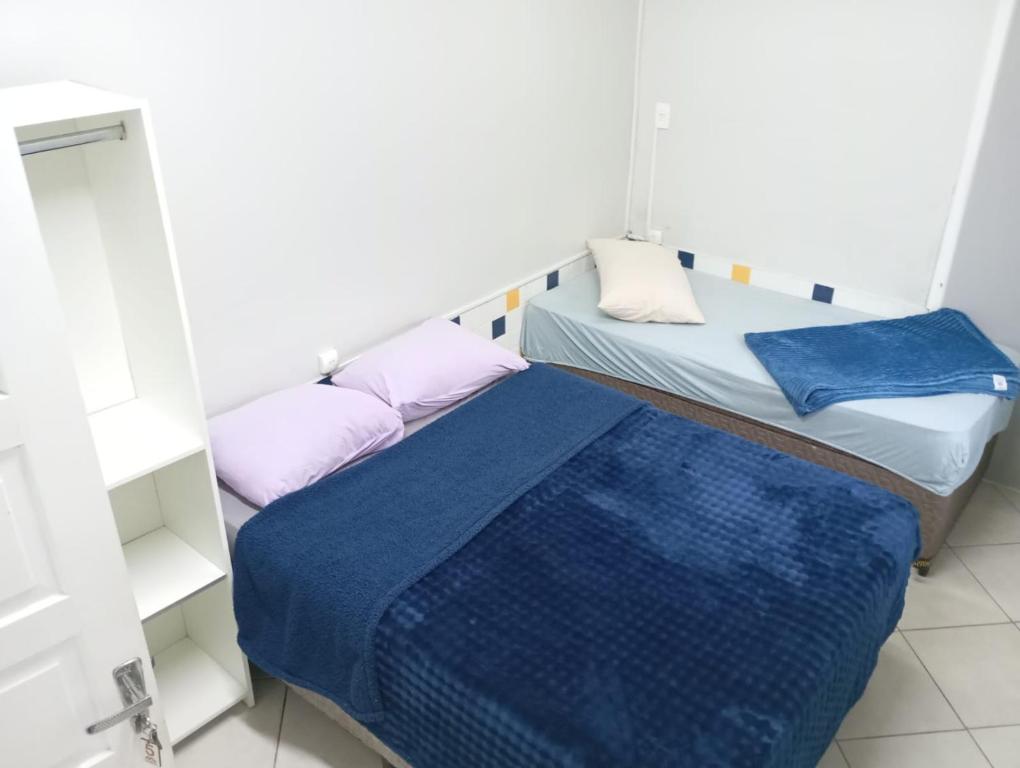a small room with two beds and a mirror at Pousada Central Quarto 5 in Joinville