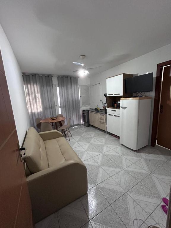 a living room with a couch and a kitchen at Quarto sala Centro in Guarapari
