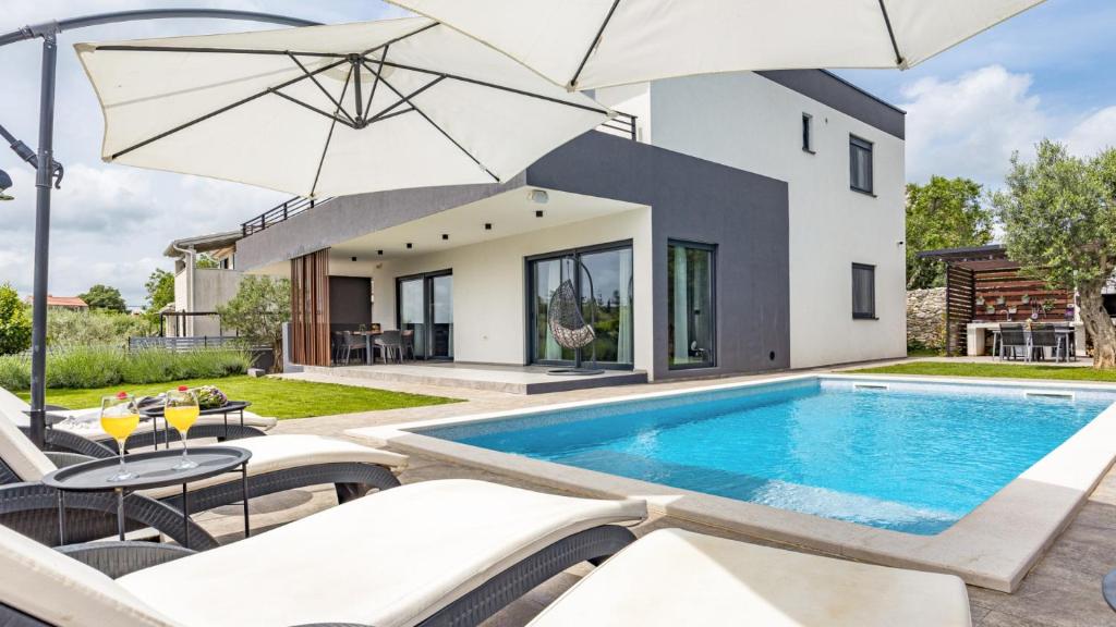 a swimming pool with two umbrellas in front of a house at Villa Kali in Krnica